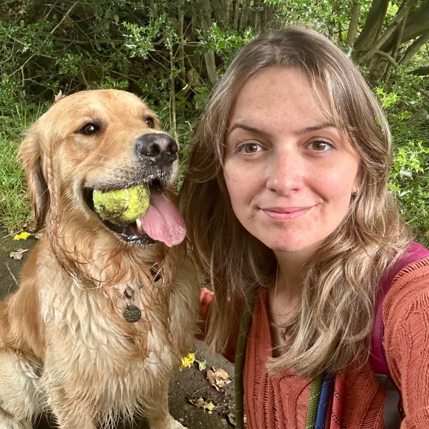 Meet the girl behind Seancara Creations Image of the creator with brown beach wave hair & her a golden retriever with his green tennis ball proudly held between his front teeth.